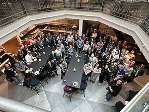 Moteris pristato renginį auditorijoje, projekcijos ekrane matomas užrašas „TCA: Internationalisation and international mobility within the Teacher training programmes in Higher Education October 7–9, 2025“, su Švedijos miestovaizdžio nuotrauka.